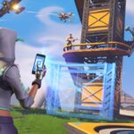 Fortnite character in a hoodie holds a smartphone to build a structure during an intense battle scene