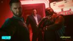 Three Cyberpunk 2077 characters in a red-lit room; tweet highlights Update 2.3 Photo Mode “What if?” with S.C.S.M. Brendan.