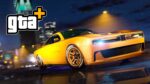 A yellow Bravado Buffalo EVX muscle car with black racing stripes and performance wheels driving at night with city lights in the background, featuring the GTA+ logo in the upper left corner.