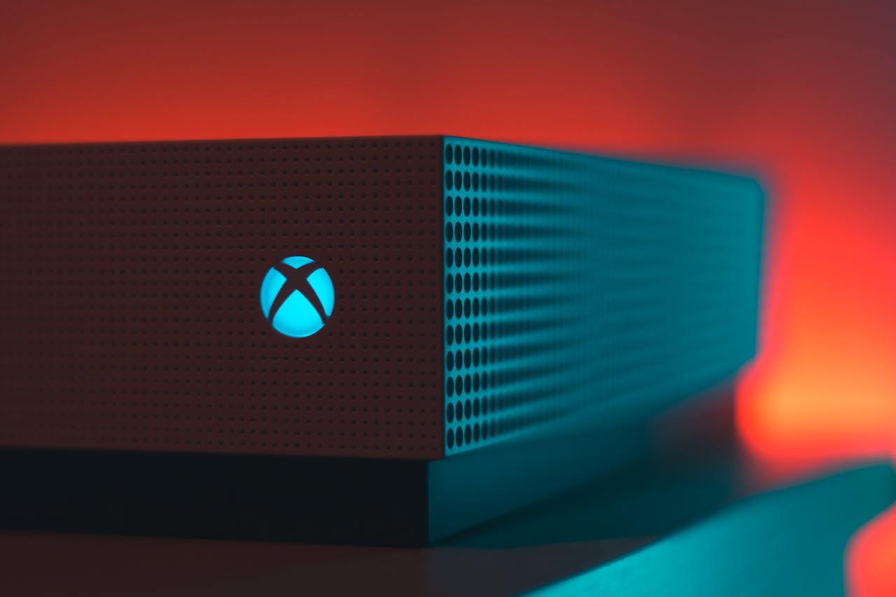 Close-up of an Xbox Series X console with illuminated Xbox logo against a red and teal background