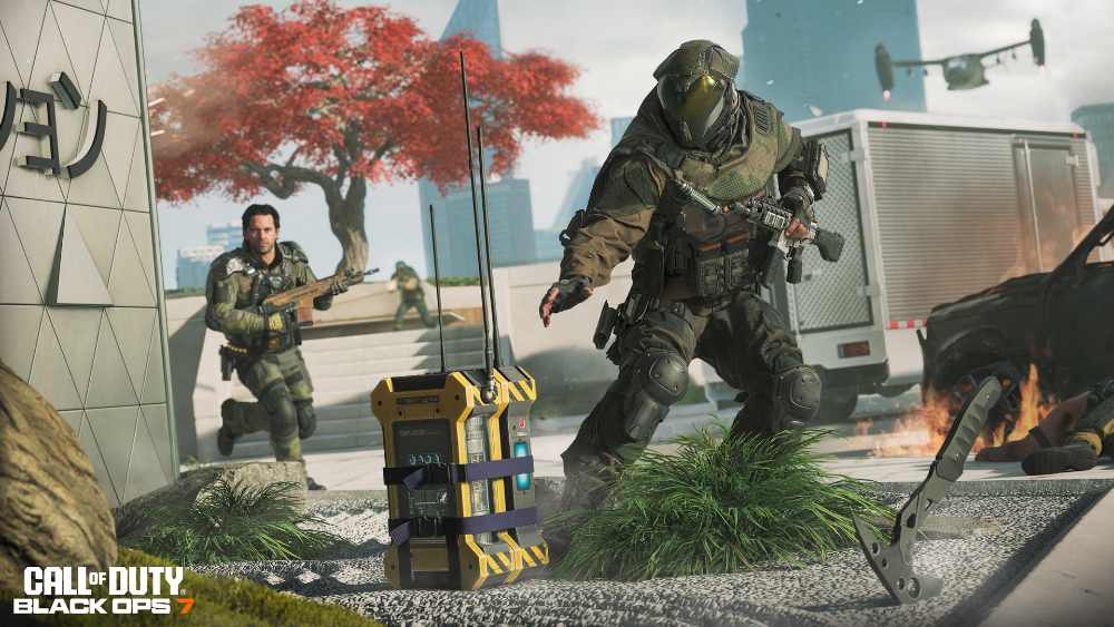 Two soldiers in tactical gear moving across an urban battlefield in Call of Duty: Black Ops 7, with one carrying what appears to be the Overload Device objective.